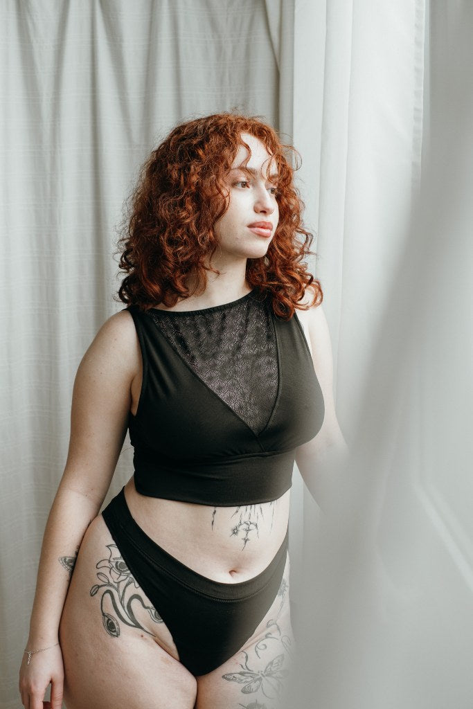 das Model mit den roten Locken trägt schöne Unterwäsche aus String und Bralette aus Lyocell Tencel